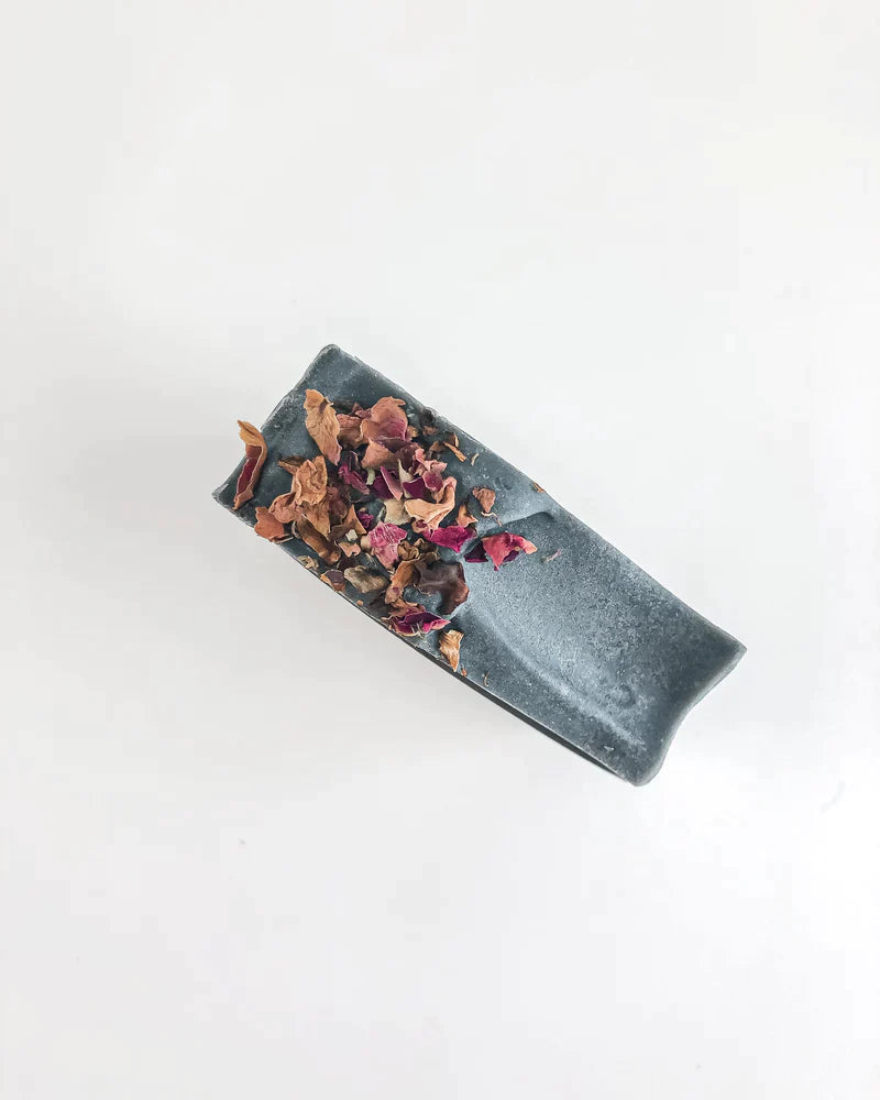 Dried rose petals on top of a charcoal bar soap made naturally for face and body by Agha Studio.