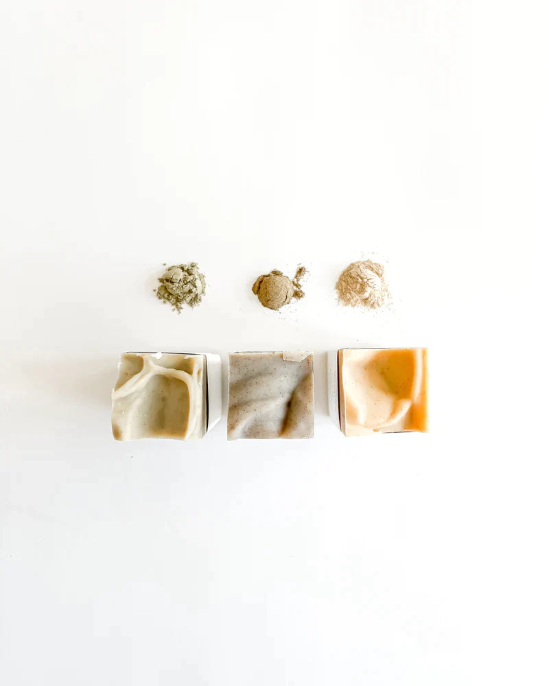 Top view of natural Korean herbal bar soaps for the face, along with powder form of ingredients by Agha Studio.