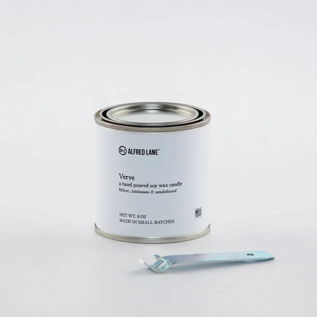 A hand-poured soy wax candle by Alfred Lane in a tin container with a tin opener.