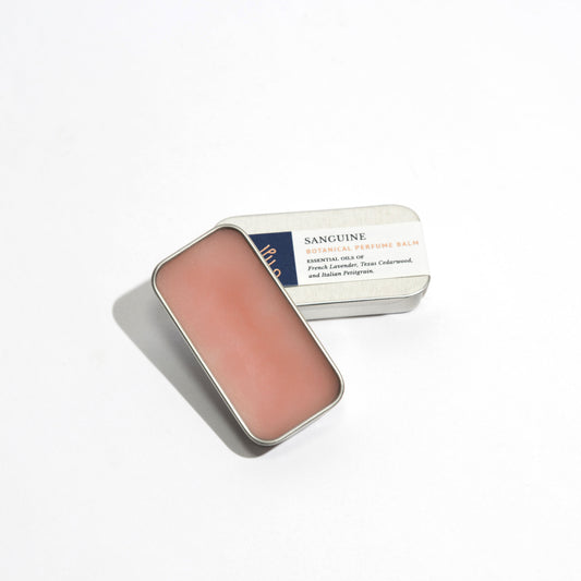 A natural perfume balm in a rectangle tin handmade with essential oils by Even keel, with the lid open showing the pink color of the balm.