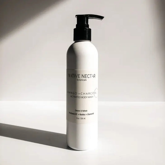 A bottle of body wash with a pump, containing shower gel made with activated charcoal with a scent of mango made by Native Nectar Botanicals to cleanse the body.