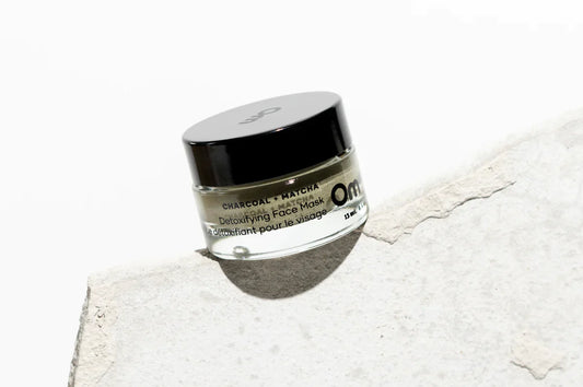 A glass jar of face mask made with charcoal and matcha to detoxify the skin made by Om Organics.